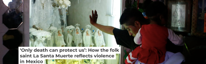 A devotee carrying his daughter rests his hand on the glass to an altar to La Santa Muerte in Tepito in Mexico City. AP Photo/Rebecca Blackwell